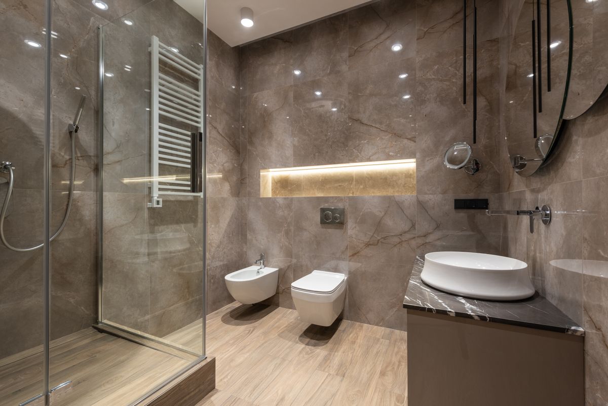 Marble-tiled walk-in shower and wet room with glass enclosure
